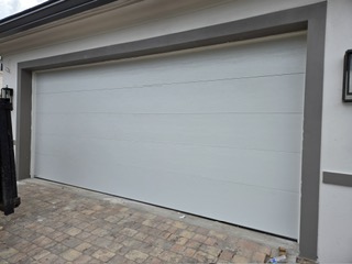 White flush panel garage door installed on a paver driveway home