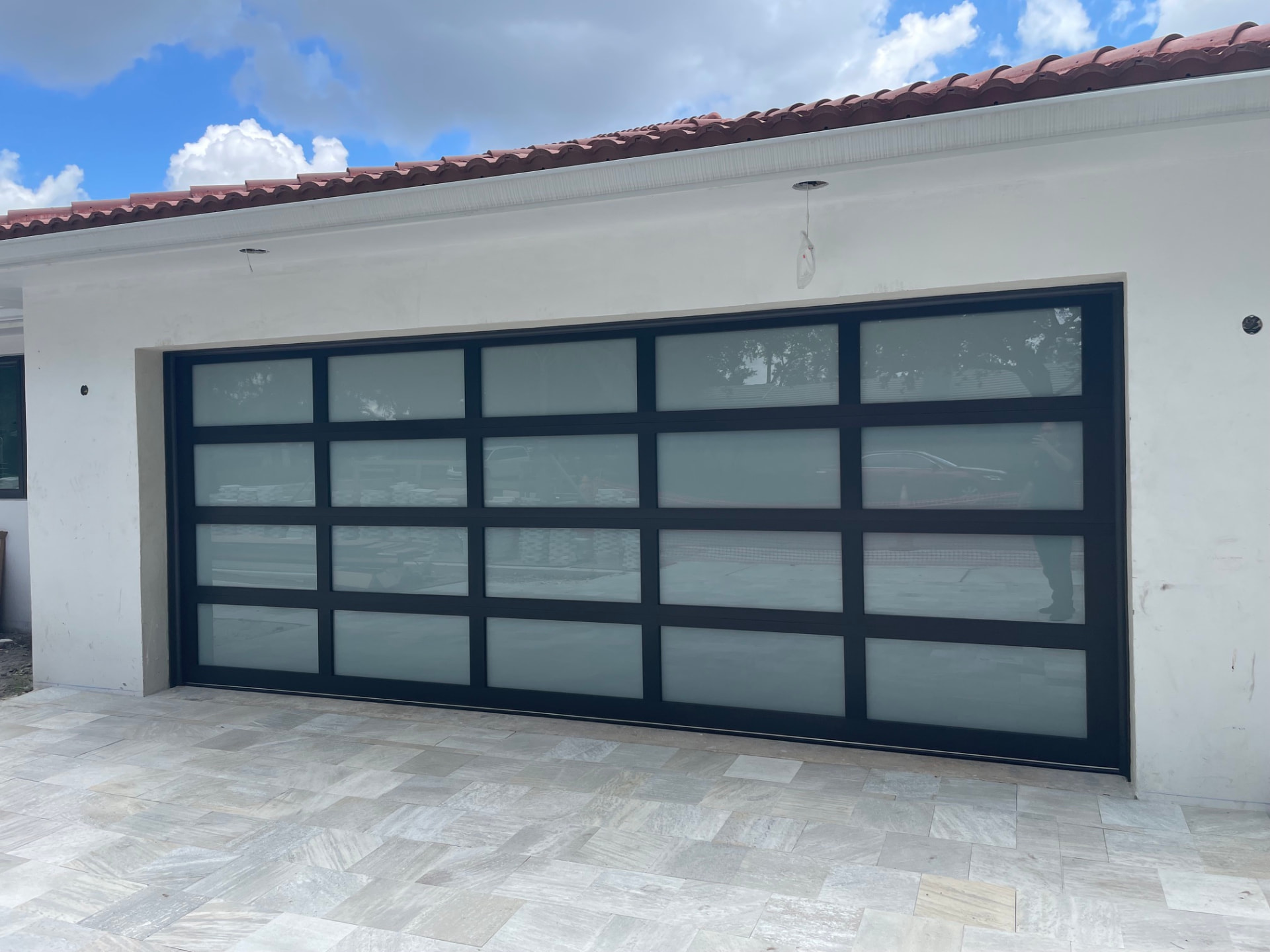Black aluminum full-view frosted glass garage door on a Miami home